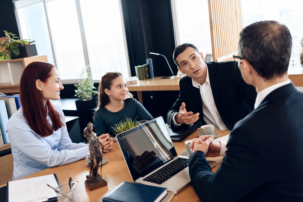 A layer and the clients seated at a table with documents.