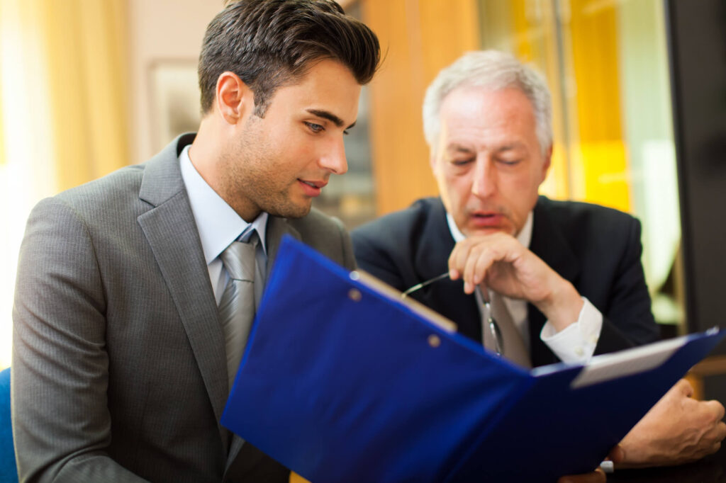 Two lawyers in suits are looking at a law file.